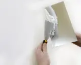 Dłoń nakłada gładź polimerową na ścianę. Choć materiał ten jest powszechnie stosowany, warto znać jego potencjalną szkodliwość.