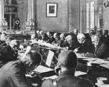 Männer in einem prunkvollen Raum diskutieren den Inhalt des Versailler Vertrags.