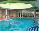 Ludzie kąpią się w basenie. Ile płaci NFZ za pacjenta w sanatorium? To pytanie nurtuje wielu, ale obraz pokazuje relaks i zdrowie.