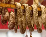 Saucissons secs, une spécialité culinaire auvergnate, pendent sur un support en bois.