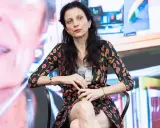 Veronica Tomassini, la cui età non è specificata, con un microfono in mano, indossa una giacca con fantasia floreale.