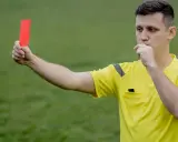 Arbitre siffle et brandit un carton rouge, signalant une faute grave. Il faut bien conjuguer "enfreindre" pour éviter ce genre de situation.