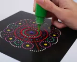 Ręka tworzy kolorowy wzór mandali, co jest formą arteterapii dla seniorów.