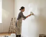 Femme appliquant une peinture à la chaux, un travail qui peut révéler des inconvénients comme des traces si mal appliqué.