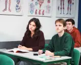 Uczniowie Akademii Humanitas uważnie słuchają lekcji biologii. Na ścianach wiszą anatomiczne plansze.