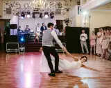 Para młoda wykonuje widowiskowe podnoszenia w tańcu, goście z zachwytem obserwują ich występ.
