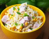 Pyszna sałatka z makaronem orzo, kawałkami szynki, kukurydzą i szczypiorkiem, podana w żółtej misce.