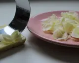 Un ustesile en métal crée des copeaux de chocolat blanc sur une assiette rose.