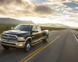 Ciemnobrązowy Dodge Ram 2500 z dwoma rzędami kół jedzie pustynną drogą o zachodzie słońca.