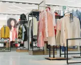 W sklepie odzieżowym widać ubrania na wieszakach i manekinach, buty na półkach. To przykład, co to merchandising – jak atrakcyjnie zaprezentować produkty.