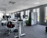 Aménagement moderne de bureaux en open space avec postes de travail équipés de plusieurs écrans, chaises ergonomiques et rangements.