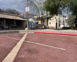 Un parque infantil con toboganes y columpios, evocando los **juegos de antes en la calle**. Un hombre pasea a su perro.