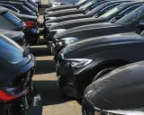 Reihe von dunklen Gebrauchtwagen, die auf einem Parkplatz stehen.