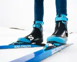 Nära bild på ett par skidpjäxor och skidor i klassisk stil, redo för en tur i snön.