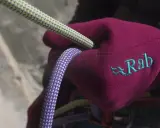 Rękawica z logo Rab, firmy znanej z odzieży i sprzętu outdoorowego, trzyma liny wspinaczkowe.