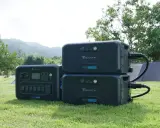 Tre Bluetti-kraftverk, ett AC300 och två B300, står på gräset. De är redo att ge både ac eller dc-ström utomhus.
