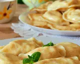 Słowackie pierogi z bryndzą na talerzu, ozdobione listkami bazylii.