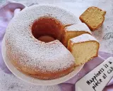 Un ciambellone soffice come una nuvola, cosparso di zucchero a velo, con fette tagliate pronte da gustare.