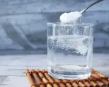Salz und Zucker werden in ein Glas Wasser gegeben, um Elektrolyte selber machen.