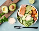 En hälsosam keto recept-bowl med lax, avokado, gurka, tomater och en krämig dressing.