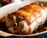 Paupiette de porc dorée et savoureuse, farcie d'herbes et cuite au four dans un plat en céramique.