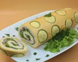 Rotolo di zucchine ripieno di prosciutto e insalata, decorato con fette di zucchina e prezzemolo su un piatto bianco.
