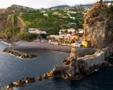 Ponta do Sol, Madeira: malerische Küstenstadt mit terrassierten Bananenplantagen, einem Kiesstrand und einer beeindruckenden Felsformation mit einem steinernen Aussichtsweg.