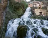 Tosender Wasserfall stürzt über Felsen, Häuser von Orbaneja del Castillo schmiegen sich an den Hang.