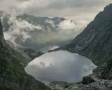 Widok na Morskie Oko, droga na Rysy w oddali. Mgła otula szczyty, odbijając się w tafli jeziora.