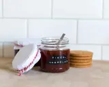 Burkar med hemlagad fikonmarmelad, perfekt för ett enkelt fikonmarmelad recept. En sked sticker upp ur den främsta burken.