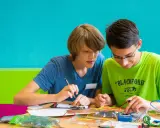 Zwei Jungen arbeiten konzentriert an einem Elektronikprojekt. Sie nutzen kreative Methoden der Gruppenarbeit, um ihre Ideen umzusetzen.