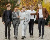 Pięciu panów w garniturach, idealnie dobranych na ślub. Pan młody w jasnym, koledzy w ciemniejszych stylizacjach.