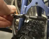 Dłoń reguluje linkę hamulca v-brake, by wyeliminować piszczące hamulce w rowerze.