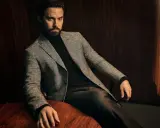 A man in a tweed blazer and dark trousers, showcasing sophisticated trouser styles.