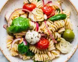 Ein bunter vegetarischer Nudelsalat mit Fusilli, Kirschtomaten, Mozzarella-Kugeln, Artischockenherzen, Oliven und frischem Basilikum.
