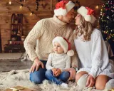 Una familia con gorros navideños, junto a un árbol de Navidad, crea una foto navidad original llena de amor y calidez.