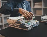 Mężczyzna w biurze przegląda stos dokumentów, co sugeruje pracę po godzinach.