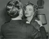 Marilyn Monroe med chockat uttryck i en scen från en av hennes filmer, hon håller fast vid en mans axel.