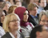 Junge Frau mit einem roten islamischen Kopftuch im Publikum.