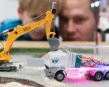 Faszination auf der **Hobby Messe Leipzig**: Ein Junge und ein Mann bestaunen eine ferngesteuerte Baustelle mit Bagger und LKW.