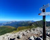Widok z **Starorobociańskiego Wierchu** na Tatry Zachodnie. Szlak turystyczny wije się po zielonych grzbietach.