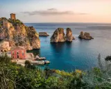 Scopri dove andare in vacanza in Italia: un borgo con torri antiche e faraglioni su un mare cristallino.