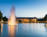 Ein beleuchteter Brunnen spiegelt sich im Wasser vor dem Neuen Schloss in der Stuttgarter Innenstadt.