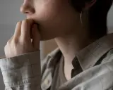 En person med fingrarna vid munnen, en stor ringörhänge i örat, utstrålar ett inre lugn.