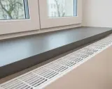 Ciemnoszary parapet idealnie komponuje się z białymi oknami, tworząc nowoczesną aranżację wnętrza.