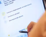 Persona haciendo un test de conducir en una tablet. La pregunta 8 es sobre una señal. ¿Cuántos test hay que hacer para aprobar el teórico?