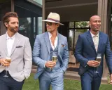 Stylish men in suits and blazers, perfect for ideas on what to wear to a wedding men. They hold champagne glasses.