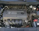 Silnik VVT-i 16 Valve z Toyoty Corolla E12. Widoczny alternator, akumulator i elementy układu dolotowego.