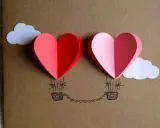 Due cuori a mongolfiera, perfetti per la festa della mamma lavoretti creativi. Nuvole bianche e un filo di cuoricini completano il disegno.