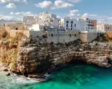 Scogliere mozzafiato e case bianche a picco sul mare turchese, perfetti **posti da visitare in Puglia estate**.